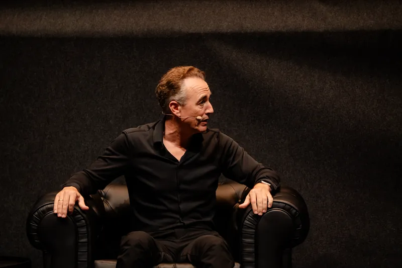 Luis Fabra Garcés interviniendo sentado en el escenario, mirando hacia el público