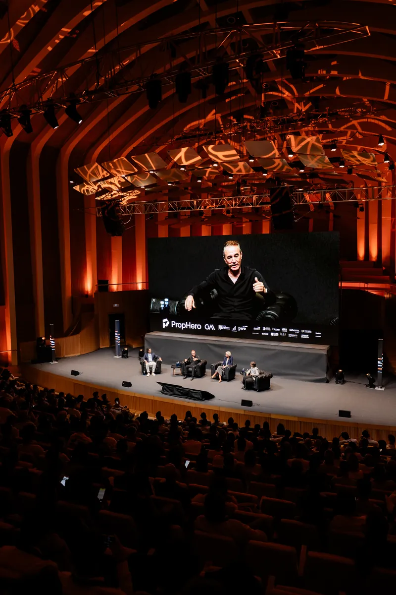 Auditorio completo con el panel en el escenario y Luis Fabra Garcés en pantalla